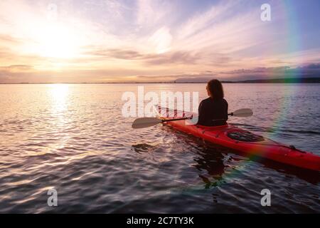 Kayak de mer dans des eaux calmes pendant un coucher de soleil coloré et vibrant. Banque D'Images