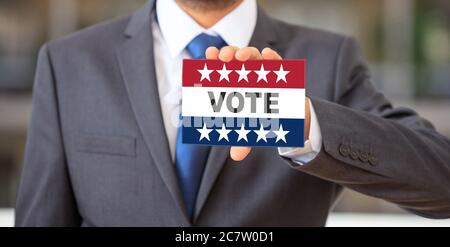 Elections aux Etats-Unis, Homme tenant une carte, VOTEZ un message texte sur les couleurs du drapeau américain avec des étoiles patriotiques. Vote sur le concept du jour des élections aux États-Unis d'Amérique. Banque D'Images