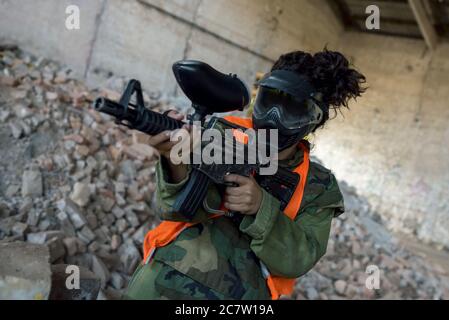 Personne dans un masque jouant paintball dans un bâtiment abandonné sous les feux Banque D'Images
