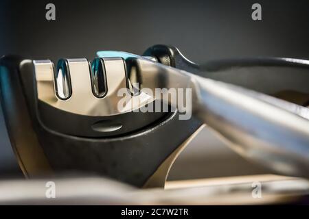 Gros plan et détail d'un couteau dans un outil de cuisine taille-couteau. Métal et chrome. Banque D'Images