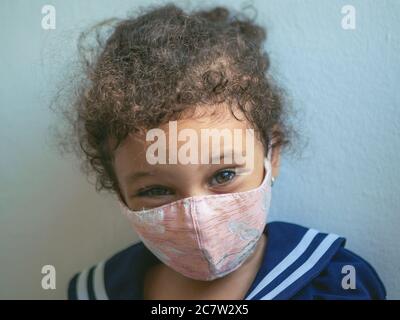 Une petite fille avec un masque avec des coeurs regarde l'appareil photo Banque D'Images