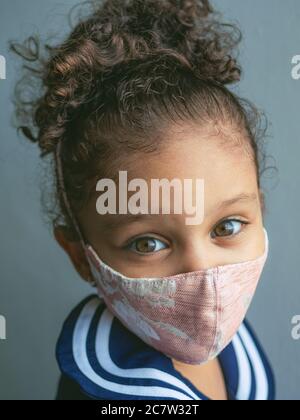 Une petite fille avec un masque avec des coeurs regarde l'appareil photo Banque D'Images