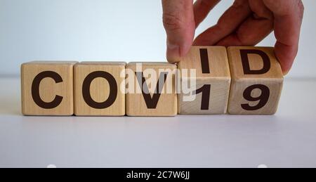COVID-19 concept de coronavirus pandémique. Cubes en bois avec l'inscription Covid-19. Cubes de retournement pour la main masculine. Banque D'Images
