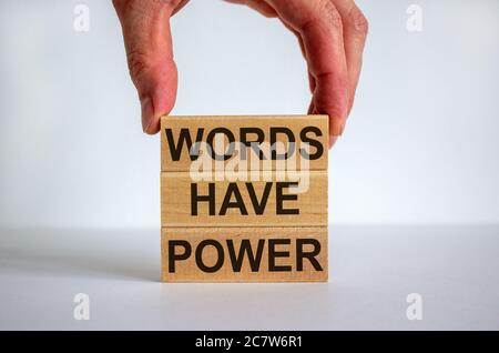 Main masculine plaçant un bloc avec le mot 'mots' sur le dessus d'une tour de blocs avec les mots 'ont puissance'. Table blanche. Magnifique fond blanc. Copier l'espace. Bus Banque D'Images