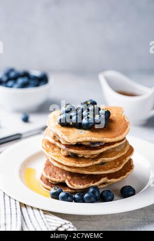 Pile de crêpes avec bleuets et sirop d'érable sur une assiette blanche, orientation verticale, espace de copie pour le texte Banque D'Images