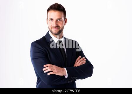 Portrait d'un jeune homme d'affaires souriant portant une combinaison et debout avec les bras croisés tout en posant sur un arrière-plan blanc isolé. Copier l'espace. Banque D'Images