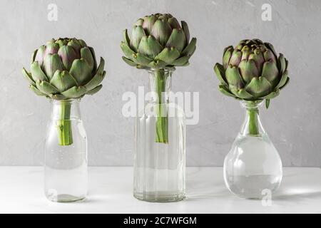 Légumes artichaut dans les bouteilles sur fond blanc. La cuisine moderne et créative reste encore une vie. Concept minimal Banque D'Images