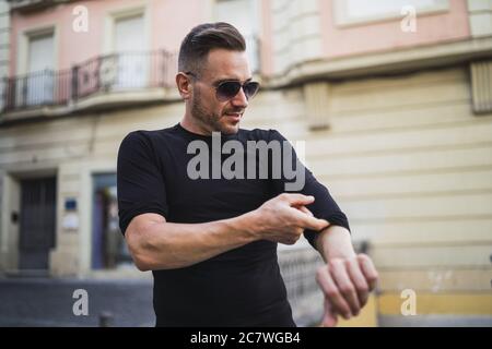 Un jeune homme de race blanche enroule ses manches de chemise dans le rue Banque D'Images