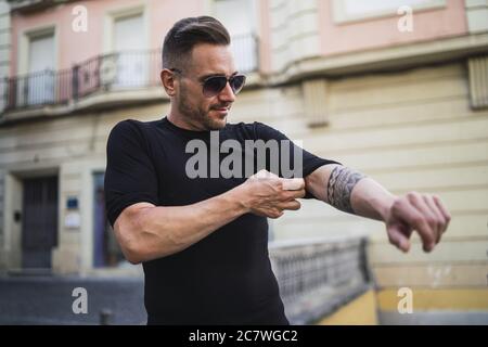 Un jeune homme de race blanche enroule ses manches de chemise dans le rue Banque D'Images