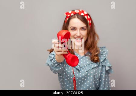 Prenez-le, répondez à l'appel ! Charmante fillette ravie de pinup donnant téléphone combiné regardant l'appareil photo, souriant regardant sympathique joyeuse, centre de contact serviable, custto Banque D'Images