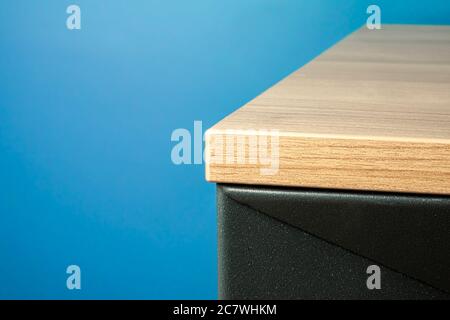 Gros plan d'un coin de table mobilier en bois massif avec fond bleu Banque D'Images
