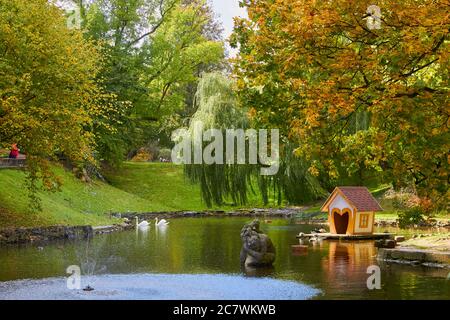 maison en bois sur un étang avec des cygnes sur l'eau en automne Banque D'Images