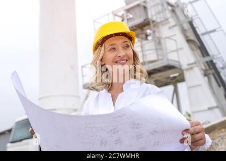 Prise de vue à angle bas d'une jeune femme d'ingénieur caucasien portant un casque sur un chantier de construction Banque D'Images
