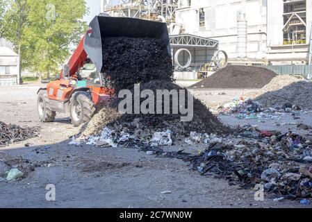 Le chargeur frontal décharge les déchets dans une usine de traitement des déchets Banque D'Images