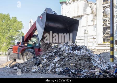 Le chargeur frontal décharge les déchets dans une usine de traitement des déchets Banque D'Images