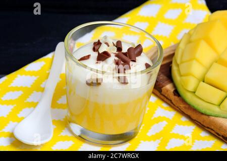 Gros plan du pudding de mangue avec de la crème fouettée et du chocolat dans un pot en verre sur une serviette Banque D'Images