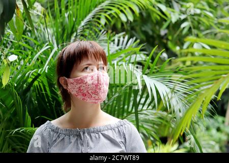 Femme dans un masque médical de protection dans une jungle. Concept de la quarantaine pendant une pandémie de coronavirus covid-19 dans un climat tropical Banque D'Images