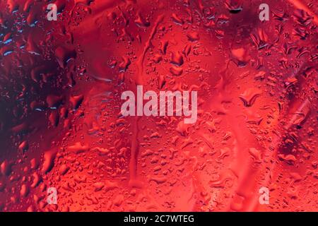 Arrière-plan abstrait rouge foncé avec gouttes de pluie sur verre Banque D'Images