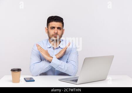 C'est la fin, la fin! Bureau de travail strict avec un ordinateur portable sur le bureau, croisant les mains montrant x signe stop geste, avertissement des problèmes. Dans Banque D'Images