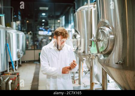 Portrait d'un technologue caucasien professionnel expert en uniforme blanc debout dans une usine pharmaceutique ou alimentaire - usine de production Banque D'Images