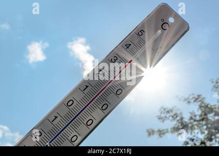 Thermomètre montre la chaleur en été contre un ciel bleu avec des rayons de soleil et des fusées de lentille, phénomène météorologique dû au réchauffement climatique avec dangereux Banque D'Images