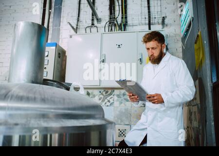 Expert en technologue de race blanche en fonctionnement de machine de production dans une usine alimentaire et en contrôle qualité et en tenue de liste de contrôle Banque D'Images