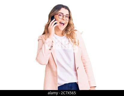 Jeune femme caucasienne ayant une conversation sur le smartphone ayant l'air positif et heureux debout et souriant avec un sourire confiant montrant le tee Banque D'Images