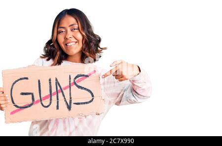 Jeune belle femme de course mixte ne tenant pas de fusils avertissement bannière sourire heureux pointant avec la main et le doigt Banque D'Images