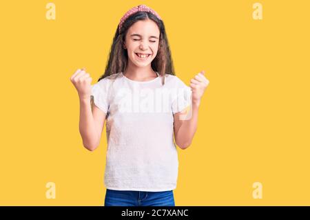 Mignon enfant hispanique fille portant décontracté blanc tshirt très heureux et excitée faisant le geste gagnant avec les bras levés, souriant et criant pour le succès. Banque D'Images