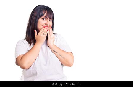 Jeune femme de taille plus portant des vêtements décontractés riant et Giggle embarrassé couvrant la bouche avec les mains, les potins et le concept de scandale Banque D'Images