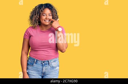 Jeune afro-américaine plus grande femme portant des vêtements décontractés pointant du doigt vers le visage et le nez, souriant gai. Concept de beauté Banque D'Images