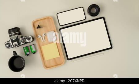 Vue de dessus du plan de travail du photographe avec tablette maquette, smartphone, appareil photo, écouteur et fournitures sur bureau blanc Banque D'Images