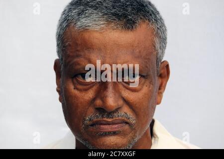 Un homme indien en colère, triste ou inquiet qui regarde un portrait sur fond blanc. Banque D'Images