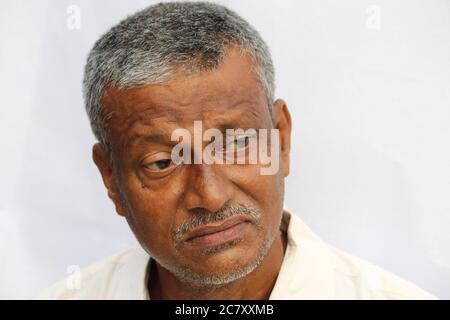 Un homme indien triste ou bien réfléchi face à un portrait sur fond blanc. Vieil homme regardant dans le côté. Banque D'Images