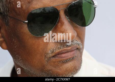 Homme indien senior vue courte portrait portant un verre de soleil et un gros plan sérieux sur fond blanc. Banque D'Images