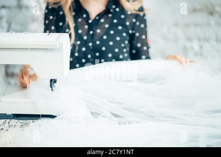 Portrait de jeune femme assise couturière et coud sur machine à coudre. Couturière travailler sur la machine à coudre. Faire un vêtement sur mesure dans son lieu de travail Banque D'Images