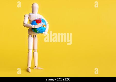 Maquette en bois avec globe entre les mains.fond jaune. Banque D'Images