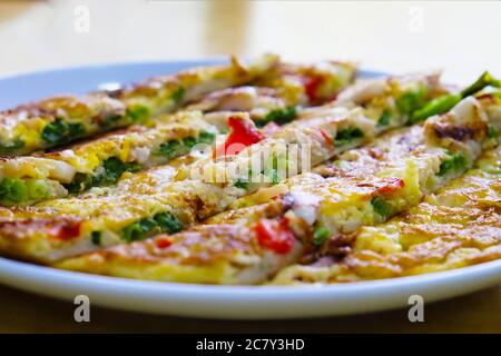 Gros plan sur une crêpe de fruits de mer (Pajeon) colorée dans une assiette blanche au restaurant coréen. Plat populaire en Corée Banque D'Images