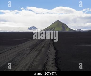 Vue sur la route de montagne de terre F210 dans le sable noir de lave Désert à la réserve naturelle Fjallabak en Islande avec le vert Maelifell montagne et myrdalsjokull Banque D'Images