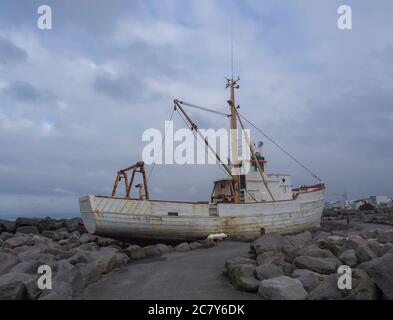 Vieux bateau de pêche abandonné rouillé, épave de navire debout sur le rocher, promenade de la rive de la mer à Keflavik, Islande, ciel bleu nuages arrière-plan Banque D'Images