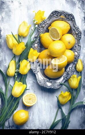 fond plat de nourriture - planche en bois vide avec belle plaque d'argent antique, beaucoup de citrons et fleurs jaunes, avec espace de copie pour le texte Banque D'Images