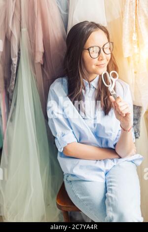 Une jolie couturière jeune a fait un nouveau vêtement en cadeau dans un atelier de couture. Banque D'Images