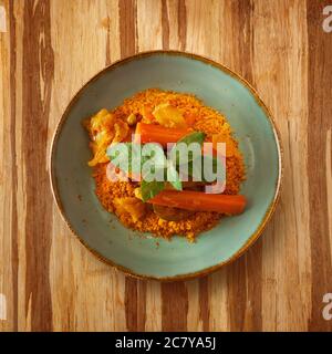 cuisine marocaine, plat cous sur une plaque de carotte, décoré de menthe sur une table en bois et espace de copie pour le texte Banque D'Images