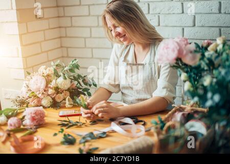 Jolie jeune femme concentrée dans des verres fleuriste travaillant dans le magasin de fleurs Banque D'Images