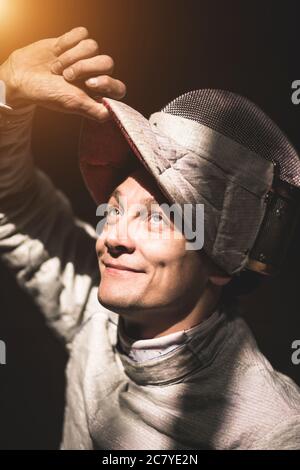 Homme portant un costume d'escrime pratiquant le loking à san et sourire Banque D'Images