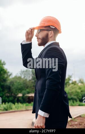 Beau, jeune ingénieur, contremaître, architecte-constructeur se penche sur la construction de la structure, à la gare, le port d'un casque de protection blanc, sm Banque D'Images