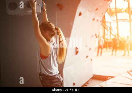 Young sport professionnel climber femme ayant une formation dans la salle de sport du mur artificiel Banque D'Images