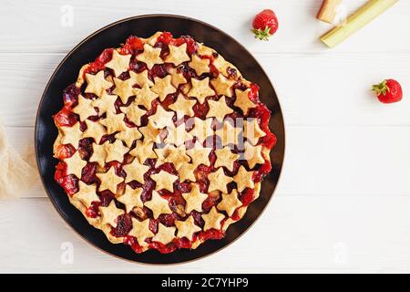 Tarte aux fraises et au rhubarbe décorée d'étoiles sur une table blanche, vue sur le dessus Banque D'Images