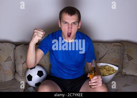 drôle d'homme regardant le football à la télévision et célébrant le but dans le salon Banque D'Images