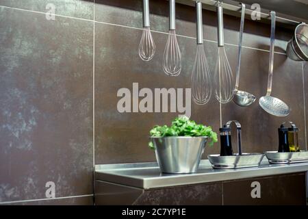 Ustensiles de cuisine en laiton, accessoires de chef. Cuisine suspendue en cuivre avec mur en carreaux blancs Banque D'Images